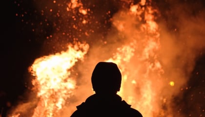 silhouette of a person standing looking into a fire 